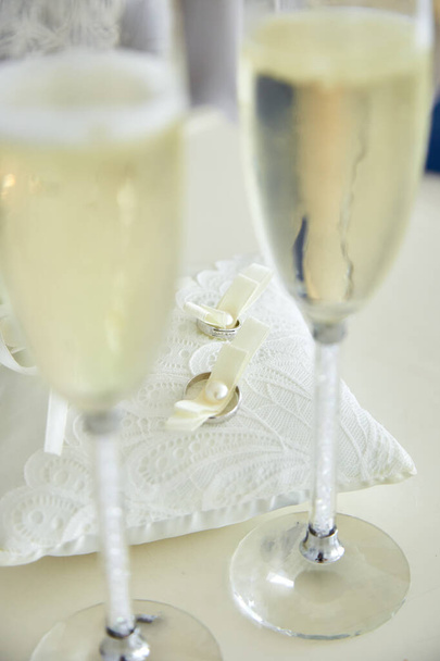 Dois copos de um champanhe e travesseiro com alianças de casamento
 - Foto, Imagem
