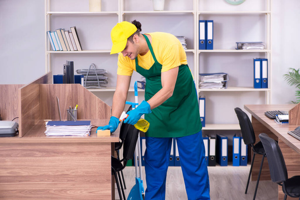 Fiatal férfi vállalkozó takarítás az irodában - Fotó, kép