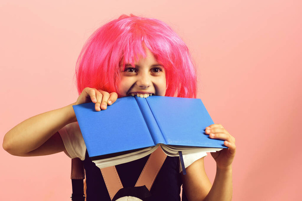 Girl bites big blue book. Back to school concept - Foto, afbeelding