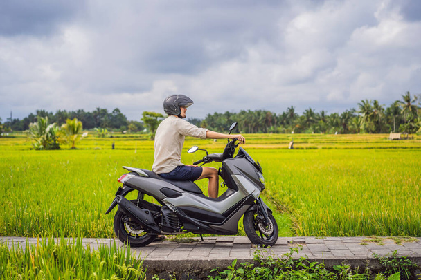 Male traveler on a bike among a rice field. Tourist travels to Bali - Foto, Imagem