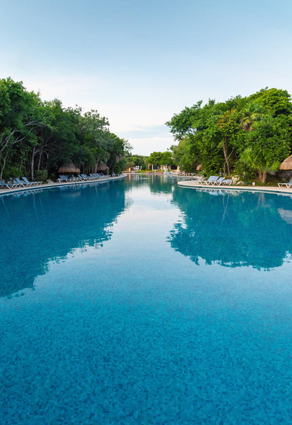 Sabahın köründe büyük bir havuz, palmiye ağaçları ve dinlenme yerleri. - Fotoğraf, Görsel