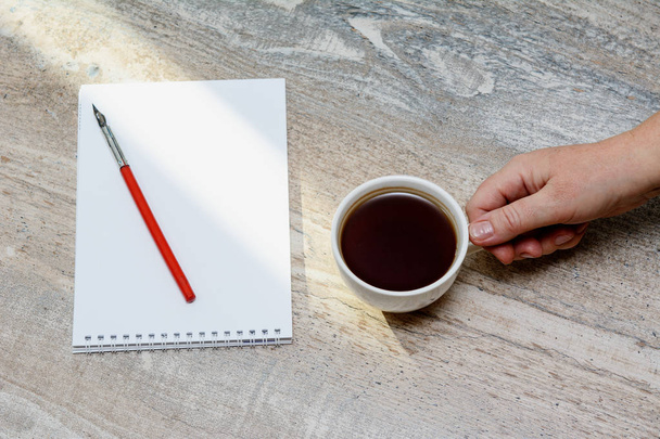 on the table is a notebook, vintage fountain pen and a female hand with a cup of coffee. Concept - coffee break, business, accountant. Cjpy space, Top view - Fotoğraf, Görsel