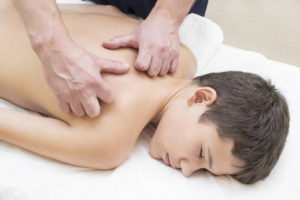 Teini-ikäinen poika saa lääketieteellisen hieronnan selästä ja kaulasta
 - Valokuva, kuva