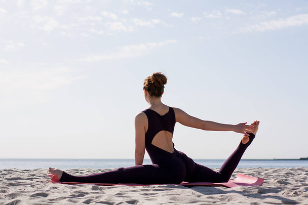 Joga kobieta ćwiczy na macie na plaży na porannym słońcu świecą  - Zdjęcie, obraz