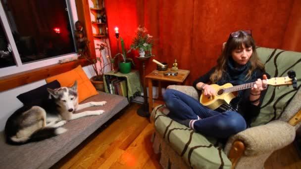 Chica jugando ukelele en sala de estar
.  - Imágenes, Vídeo