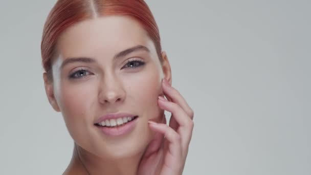 Studio portrait of young, beautiful and natural redhead woman applying skin care cream. Face lifting, cosmetics and make-up concept. - Imágenes, Vídeo