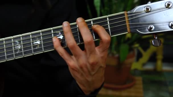 Mies soittaa akustista kitaraa kotona
 - Materiaali, video