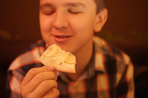 teen boy mangia la pizza e gode, primo piano godendo e assaporando
. - Foto, immagini