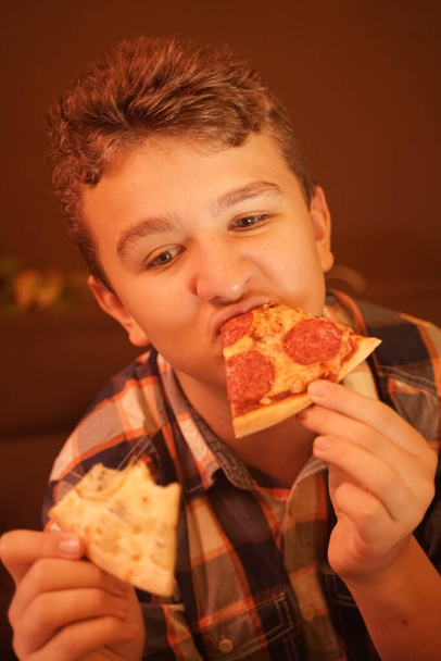 teen boy eats pizza and enjoys it, closeup enjoying and savoring. - Foto, imagen