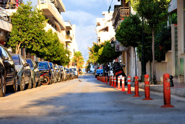 La parte peatonal de la carretera está dividida por columnas rojas en una calle de la ciudad a la luz del sol.
. - Foto, imagen