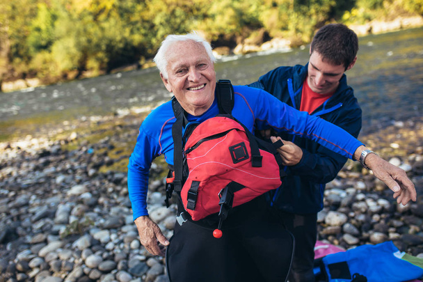 Hombre mayor preparándose para la excursión en kayak en un río de montaña. - Foto, imagen