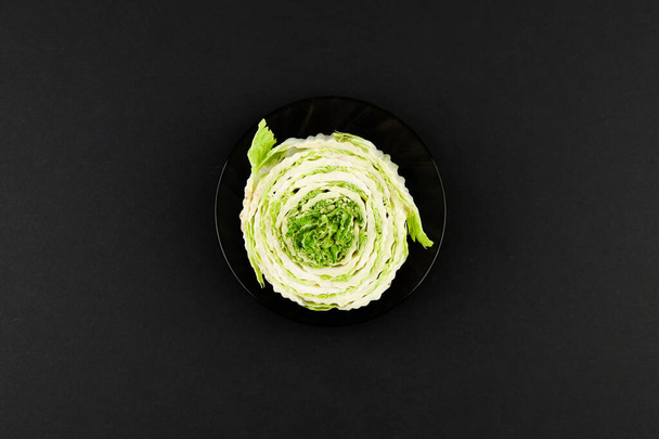 Beijing cabbage on a black background. Permanent manager of fresh, dietary green and white Peking cabbage. In the shape of a cutout. Beijing cabbage in hand - Photo, Image