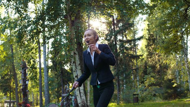 Woman with microphone works and plays badminton - Valokuva, kuva