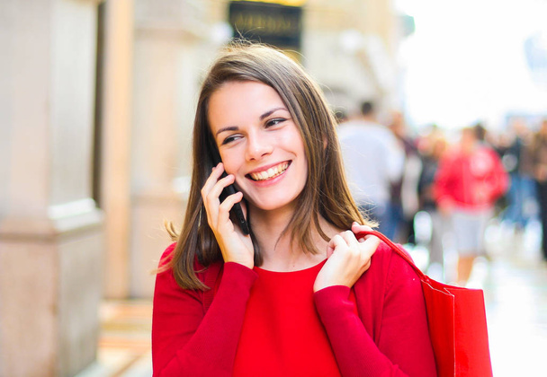 Young woman shopping with a Christmas outfit while walking and speaking on the phone - Foto, imagen