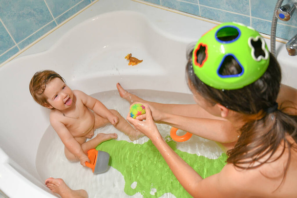Bebé de baño conjunto y mamá. Las mamás lavan a las chicas en el baño. Un símbolo de limpieza y educación higiénica
. - Foto, imagen
