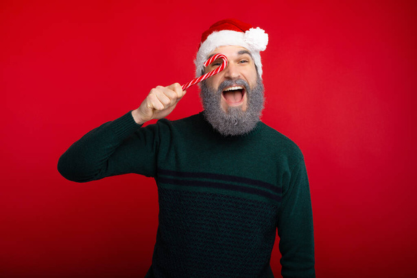 Cheerful hipster man with white beard holding red xmas candy - Foto, immagini