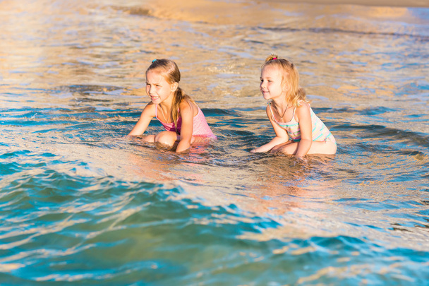 Two adorable kids playing in the sea on a beach - Foto, Imagen