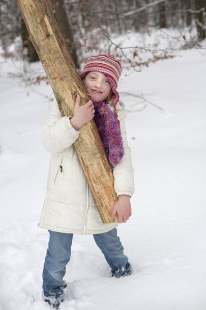 A strong girl holding a tree trunk. - Photo, Image