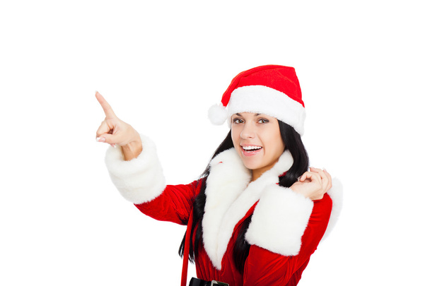 Woman in Santa Clause costume pointing to copy space - Photo, image
