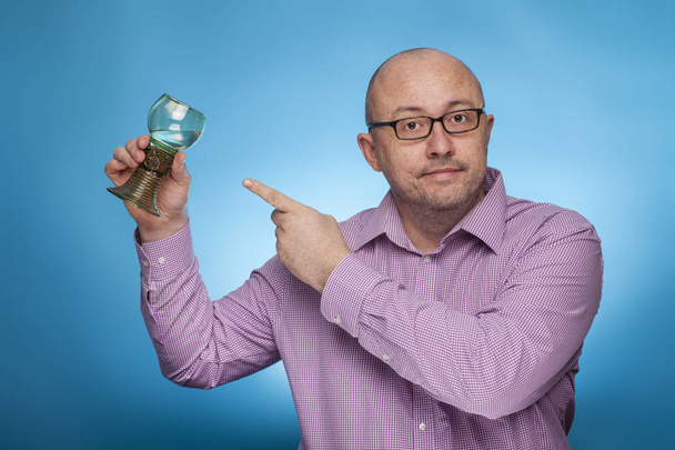 ein Geschäftsmann im zackigen Hemd, der mit dem Zeigefinger auf ein antikes Glas Wein zeigt - Foto, Bild
