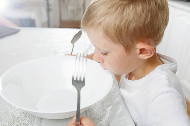 A fiú egy üres tányért néz. - Fotó, kép