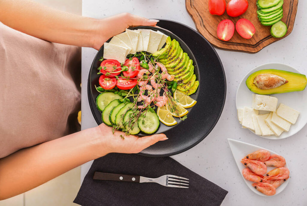 Frau mit Teller mit gesundem Salat am Tisch - Foto, Bild