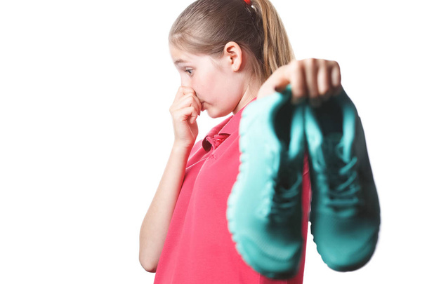 chica sostiene apestosas zapatillas de deporte y cierra la mano con la nariz
 - Foto, imagen