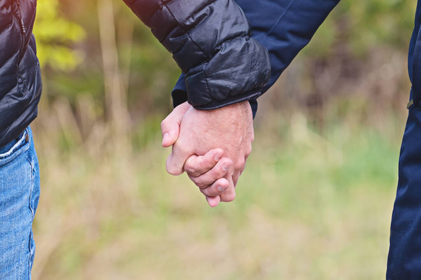 Two men holding hands in jackets outdoor, closeup view - Fotografie, Obrázek