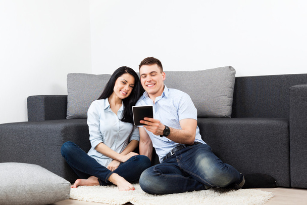 Молода пара щаслива усміхається, використовуючи планшетний сенсорний екран вдома
 - Фото, зображення