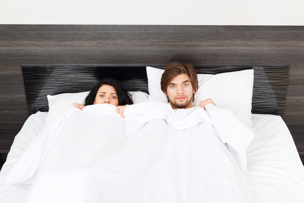 Surprise couple lying in a bed - Фото, зображення