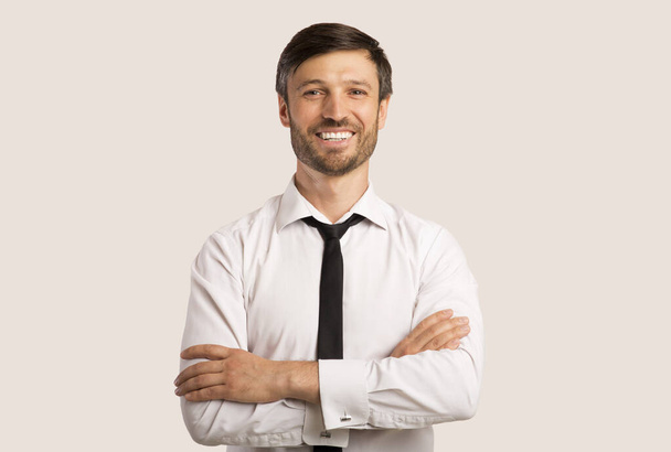 homem de negócios sorrindo cruzando as mãos de pé sobre fundo branco
 - Foto, Imagem