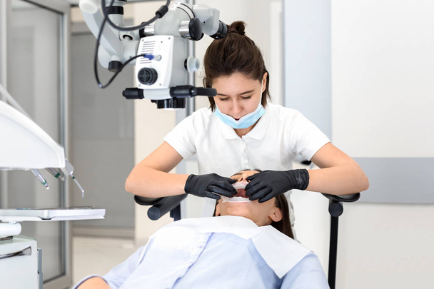 Vrouwelijke tandarts maakt zijn patiënt klaar voor de tandheelkundige chirurgie - Foto, afbeelding