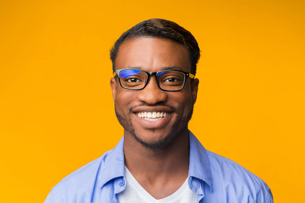 Afrikkalainen amerikkalainen mies hymyilee kamerassa poseeraa yli keltainen tausta
 - Valokuva, kuva