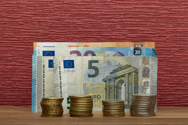 Euromunten en -biljet op de bordeauxrode achtergrond - Foto, afbeelding
