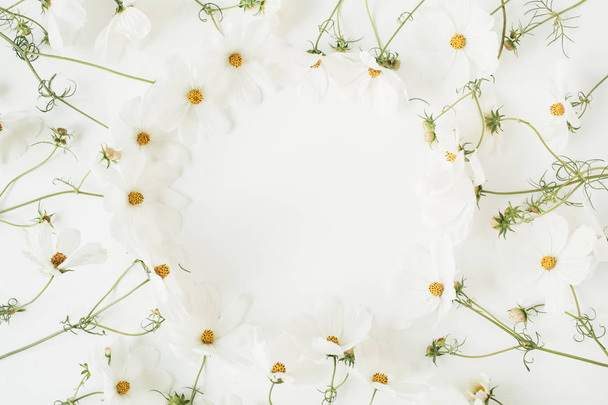 ミニマルなコンセプト。白い背景に白いデイジーカモミールの花で作られたリース。創造的なライフスタイル、夏、春のコンセプト。コピースペース,フラットレイアウト,トップビュー. - 写真・画像