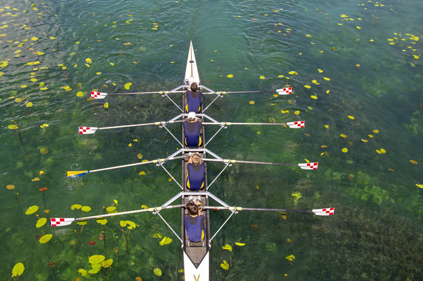 Men's quadruple rowing team on turquoise green lake - Photo, Image