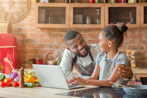 Усміхнений тато і дочка шукають смачний рецепт, використовуючи ноутбук
 - Фото, зображення