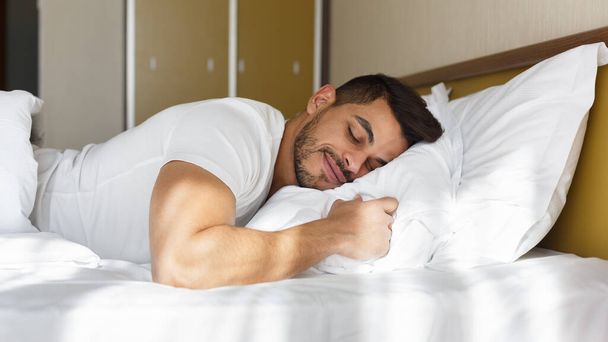 junger Mann schläft friedlich in seinem Bett - Foto, Bild