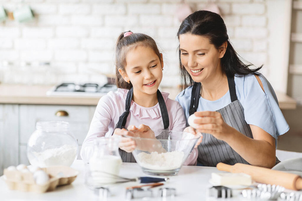 Little girl and her beautiful mother having fun cooking together - Photo, Image