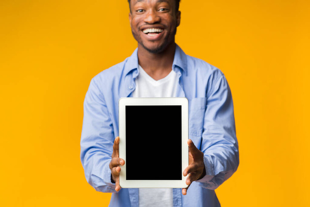 Musta kaveri näyttää tyhjän tabletin näytön keltaisella taustalla, Mockup
 - Valokuva, kuva