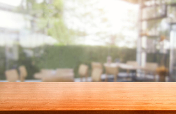 Drewniany stół w rozmazanym tle nowoczesnej restauracji lub kawiarni z pustą przestrzenią na egzemplarzu na stole do wizualizacji produktu. Koncepcja projektowania licznika wnętrz restauracji. - Zdjęcie, obraz