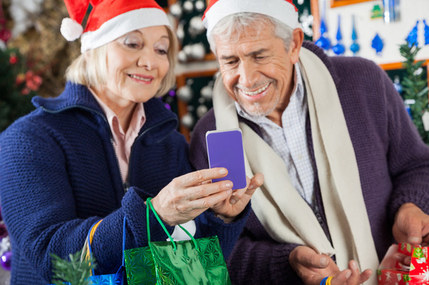 Senior Couple Using Mobilephone At Christmas Store - Foto, afbeelding
