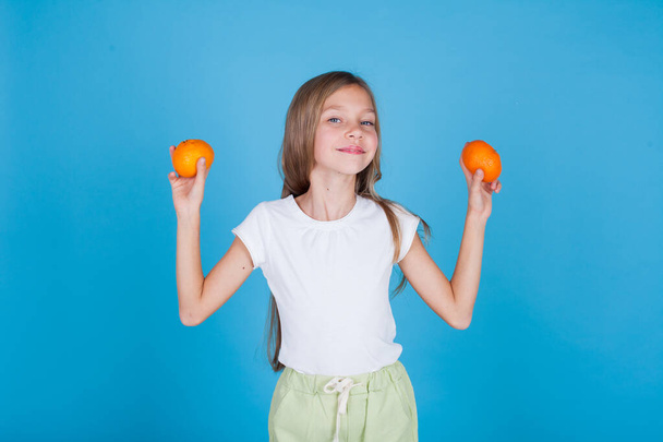 mooi klein meisje met een oranje fruit - Foto, afbeelding