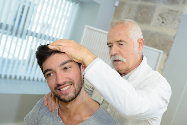 fizjoterapeuta badający męskiego pacjenta rozciągającego się - Zdjęcie, obraz