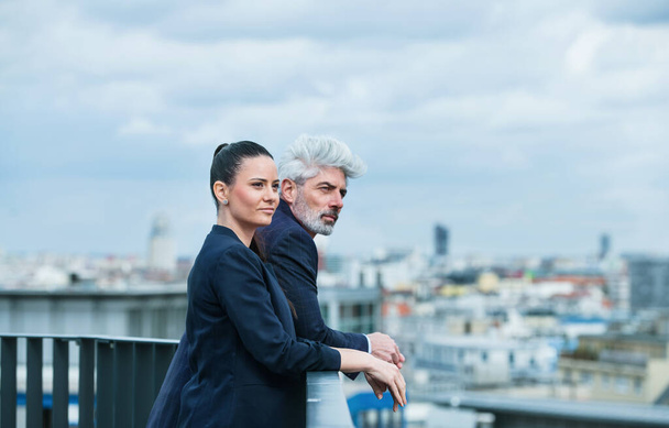 A businessman and businesswoman standing on a terrace, talking. - Foto, immagini