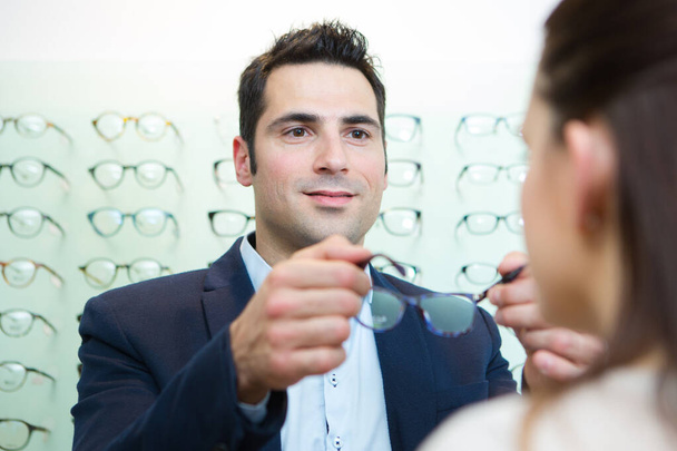 attractive optician assisting female testing new glasses - Фото, изображение