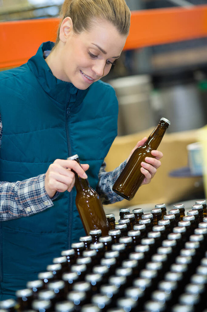mladá pracovnice stáčení piva do skleněných lahví v pivovaru - Fotografie, Obrázek