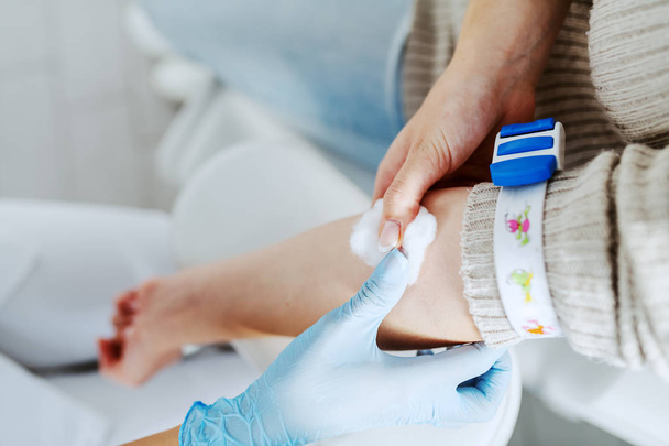 Close up of lab assistant putting absorbent cotton on patient arm after taking blood sample. - Fotografie, Obrázek