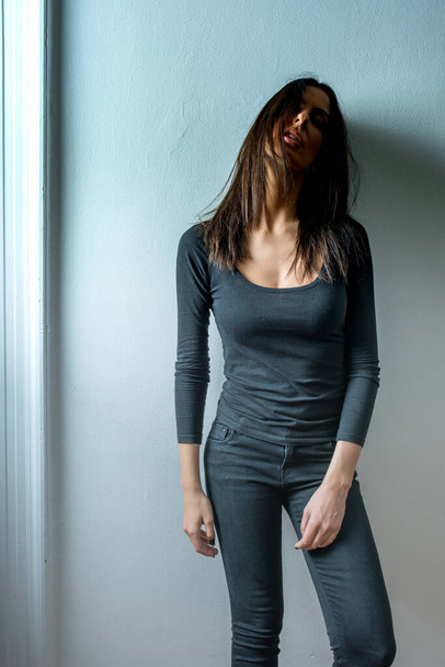 Dark mood portrait of a woman in front of a wall - Zdjęcie, obraz