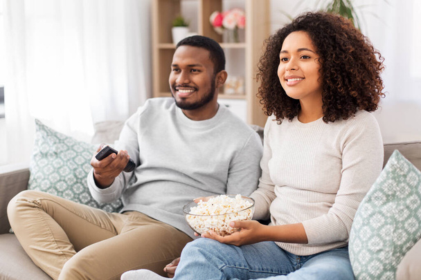 african couple with popcorn watching tv at home - Fotó, kép